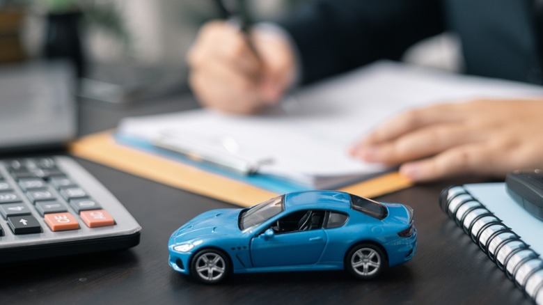 A bluish artifact car adjacent paperwork that is being signed