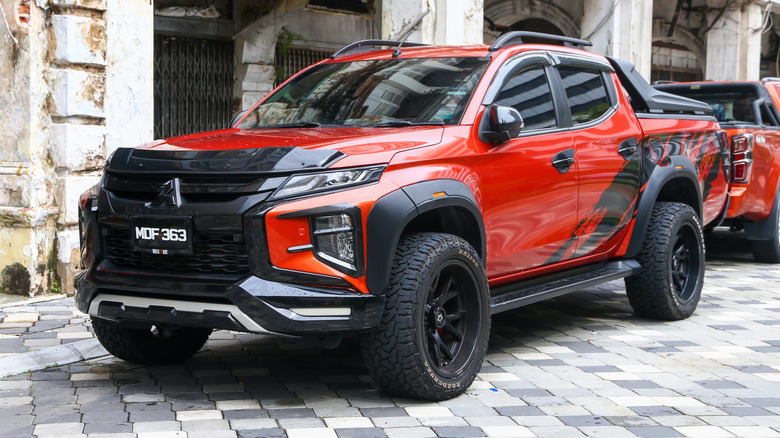 A red lifted Mitsubishi Triton pickup truck