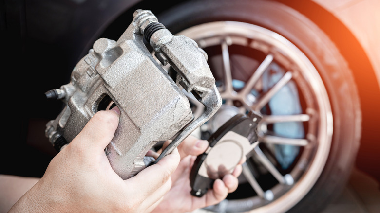 Mechanic holding brake caliper and pad