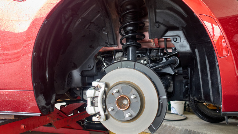 The front of a car with the wheel removed to reveal the brakes and suspension struts