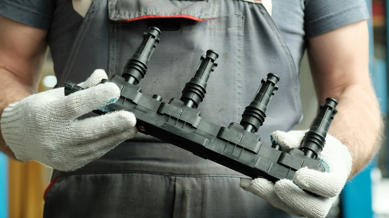 A mechanic holding a new set of ignition coils