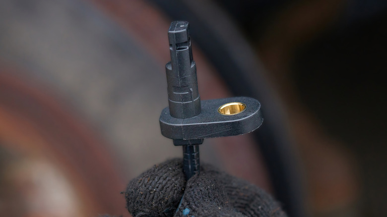 A mechanic holding a new ABS sensor
