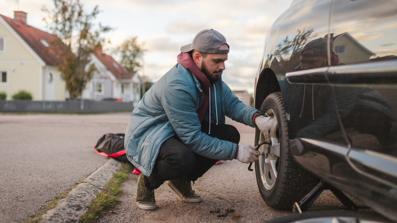 A man tightening up the wheel bolts on a car