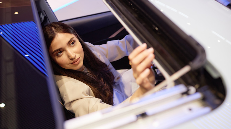 A young woman inspecting a vehicle's sunroof