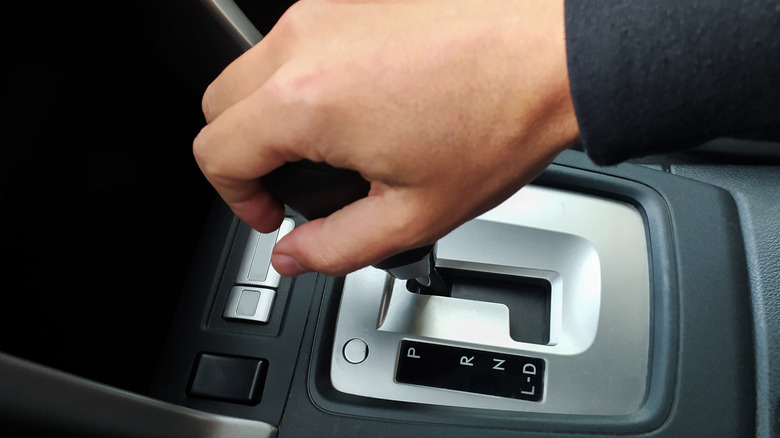 A driver's hand on the gear shift lever of an automatic car