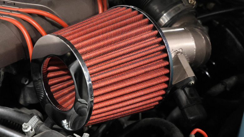 A red conical air filter in a car's engine bay.