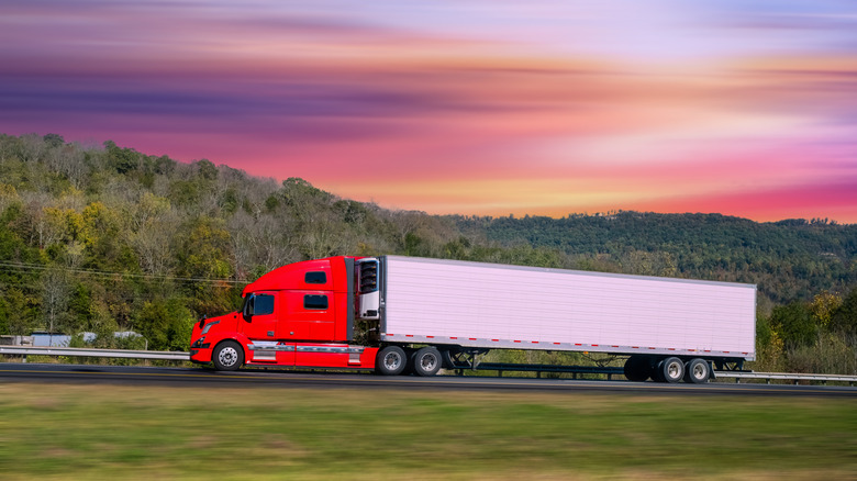 A semi truck tractor with tandem axles plying on a highway.