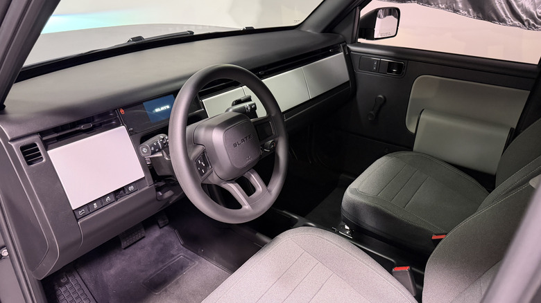 Interior of a Slate truck with seats, a steering wheel, and a bare dashboard