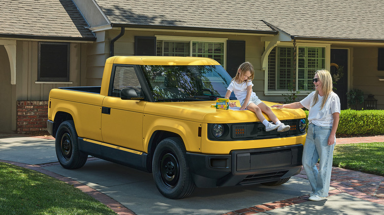 A mother and her daughter hanging out with a Crayola yellow Slate Truck.