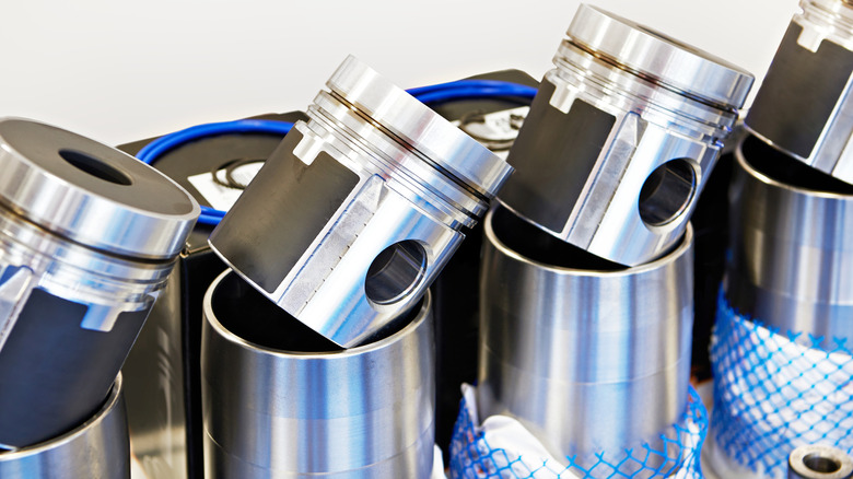 A series of pistons and cylinder sleeves ready for installation into an engine block