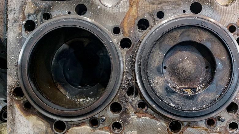 Two corroded cylinders with sleeves and pistons in a bare engine block