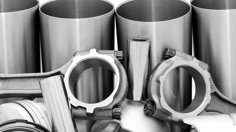 A set of connecting rods and engine block cylinder sleeves against a white background