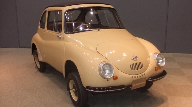 A cream-colored Subaru 360 "Ladybug" on a showroom floor.