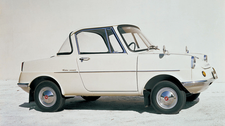 A side profile shot of a white 1960s Mazda R360 coupe against a plain white background.