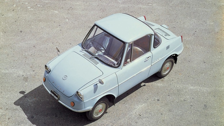 A light blue Mazda R360 viewed from above with the sun dropping a front shadow