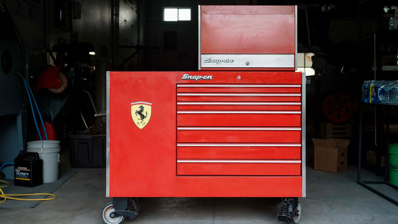 A red Snap-On toolbox with a Ferrari logo on the side, set in a dark garage.