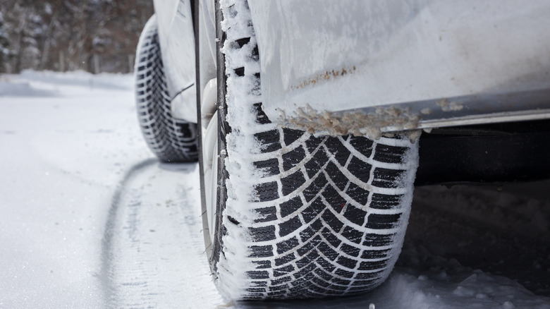 A low perspective of a snowy tire on a vehicle