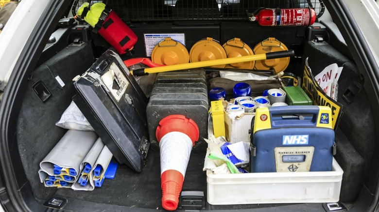 A full cargo area of a police car, featuring traffic cones, a fire extinguisher, and various other supplies