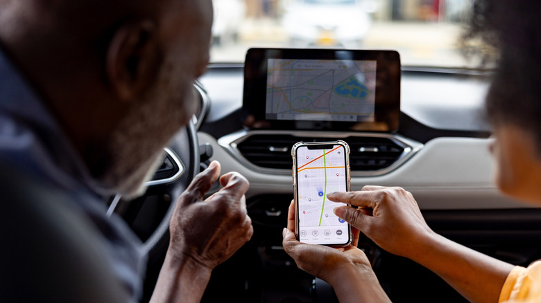 A couple look at a map on their phone and touch screen.