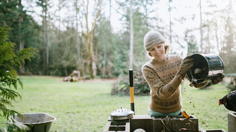A woman tosses food scraps into a compost bin.