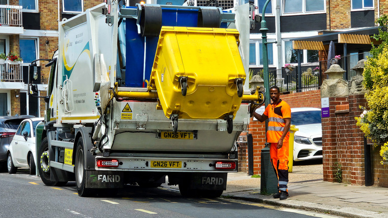 A trash truck picks up a bin on an urban street.