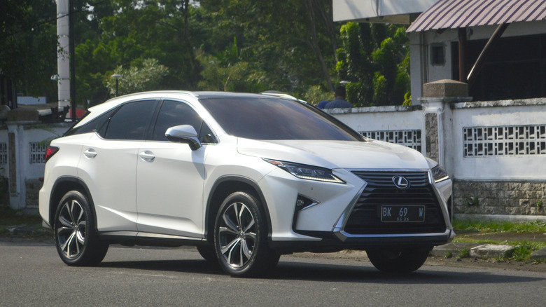 Medan, North Sumatra, Indonesia - February 20, 2026: a white Lexus RX 200t japanese luxury crossover SUV driving on public road in daytime city traffic. The fourth generation of Lexus RX model.