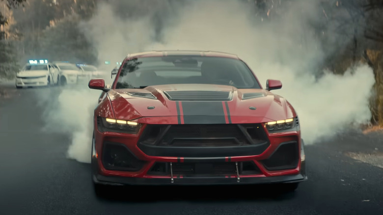 A red 2026 Shelby Super Snake pursued by police vehicles in the movie 'The Mongoose.'