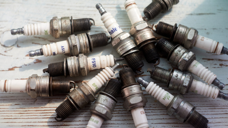 A collection of old and used spark plugs on a wooden table