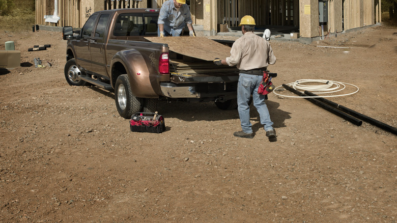 Construction workers loading material onto a truck bed.