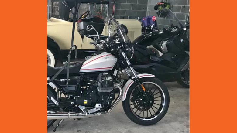 A silver Moto Guzzi that's sort of visible amongst a crowded garage