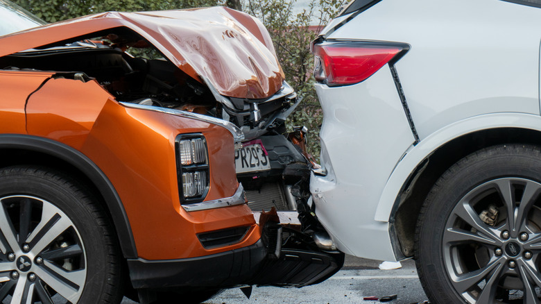 A close-up showing an orange car colliding with the back of a white SUV.