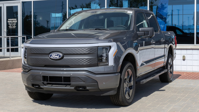 A front-end view of a gray Ford F-150 parked in front of a showroom.