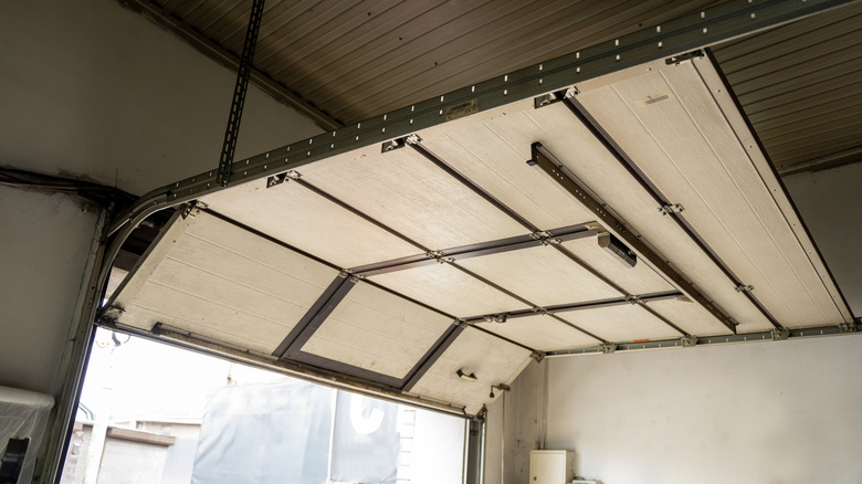 A broken overhead garage door coming off its tracks.