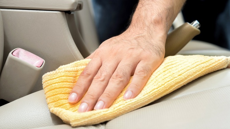 Hand wiping leather car seat with microfiber cloth
