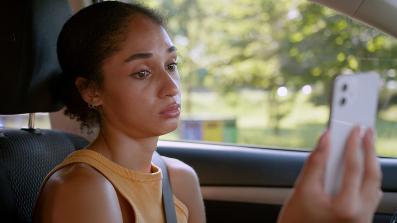 A woman looks at her phone while driving.
