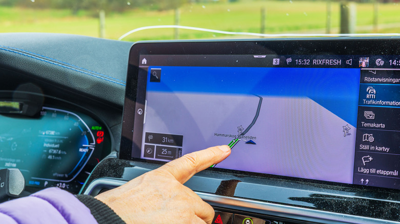 A driver interacting with the touchscreen of a BMW.