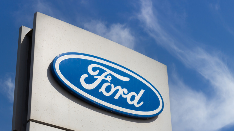 Close-up Ford brand logo on against blue sky background.