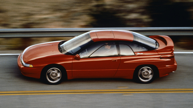 Red Subaru SVX sports car high left view driving on a two-lane road
