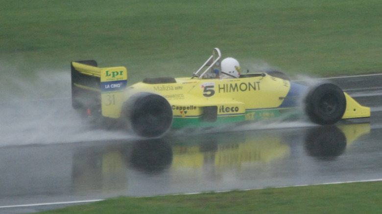 A yellow Coloni FC188B driving in 2008 at Donington Park during a rainstorm