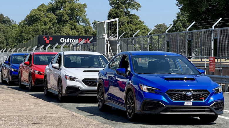 A photo of four red white and blue WRXs parked in the pits at Oulton Park