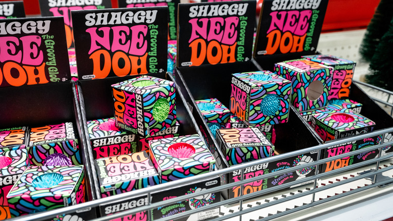 Boxes of brightly colored NeeDoh squish toys on a shelf at a retailer.
