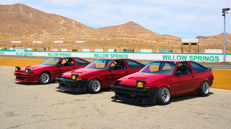 The many Lolas of "Drifter", three red Toyota AE86s line up against the pit wall at Willow Springs in California.