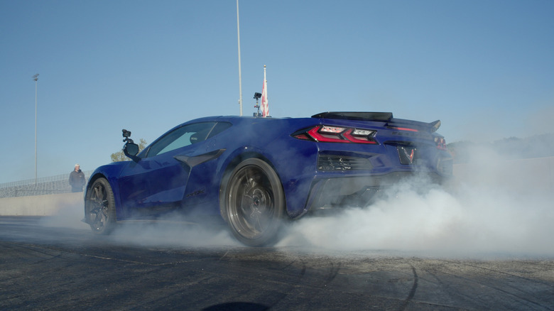 A deep blue Chevrolet Corvette ZR1X viewed from behind as it generates a massive cloud of tire smoke during a burnout at a drag strip