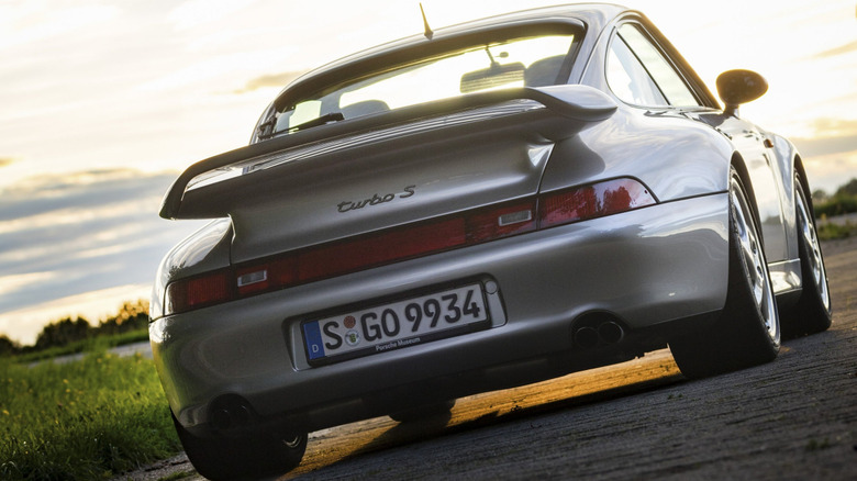 A low-angle, rear three-quarter view of a silver Porsche 911 (993) Turbo S parked during sunset.