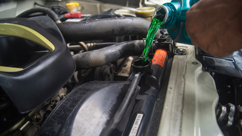 A mechanic pouring fresh coolant into a truck's radiator