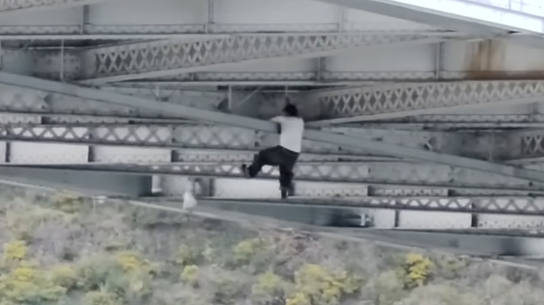 A car thief hangs on the crossbeams underneath the Bay Bridge.