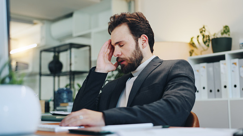 Person sitting at a computer looking tired and frustrated after finding out they have a lapse in their insurance coverage.