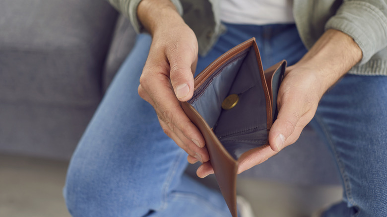 Person with an open wallet with very little money in it