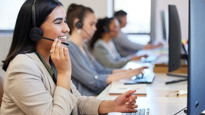 People in a call center answering calls and smiling