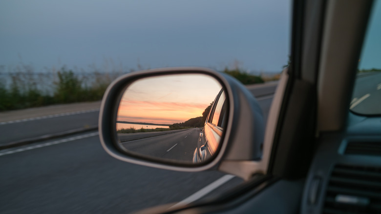 Rearview mirror with a view of the sun setting.